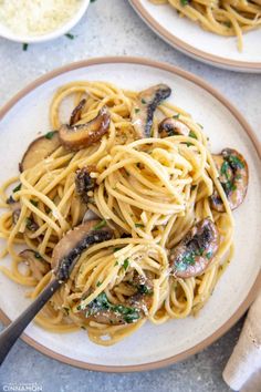 two plates of pasta with mushrooms and parmesan cheese