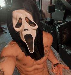 a shirtless man wearing a white mask with his tongue out and mouth wide open