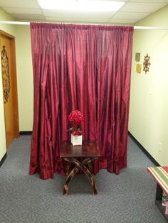 a room with red curtains and a small table in front of the curtained door