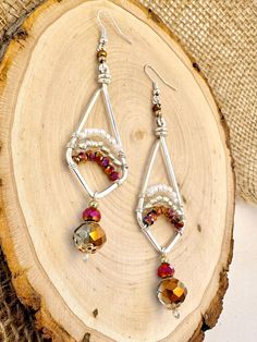 a pair of earrings sitting on top of a piece of wood next to a tree