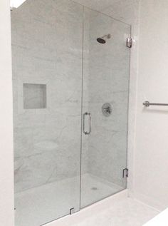 a glass shower door in a white bathroom