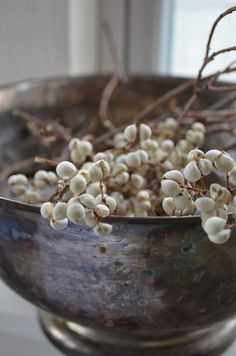 a metal bowl filled with white flowers on top of a table