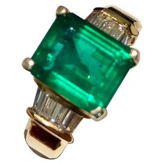 gorgeous showcasing estate ring centering an Intense perfect medium green Emerald-cut Zambian genuine emerald 2.90 Carats. The emerald is very clean. The side diamonds are baguette-cut total of 0.38ct and are color H-SI clarity. Ring size: 6 14K yellow gold Classic Emerald Ring With Baguette Cut, Classic Green Baguette Cut Diamond Ring, Timeless Green Jewelry With Baguette Diamonds, Timeless Green Baguette-cut Emerald Ring, Timeless Green Baguette Cut Emerald Ring, Timeless Baguette Cut Green Emerald Ring, Classic Green Emerald Ring With Baguette Diamonds, Classic Green Diamond Ring With Baguette Diamonds, Green Emerald Baguette Cut Diamond Ring