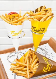 french fries are served in paper cups on a tray