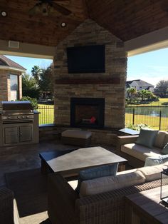 an outdoor living room with fireplace and grill