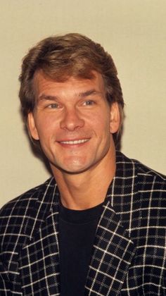 a man in a black and white jacket smiling at the camera with a smile on his face