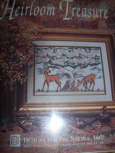 the front cover of a cross stitch book with an image of two deers and a tree