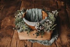 an arrangement of air plants in a basket on a wooden surface with fur around it