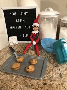 an elf is sitting on top of a cookie sheet with cookies in front of it