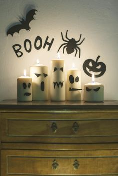 halloween candles sitting on top of a dresser next to a wall with the word boo