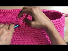 someone is crocheting a pink basket with yarn