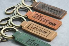 four leather keychains with the names of three different companies on them, one is brown and one is green