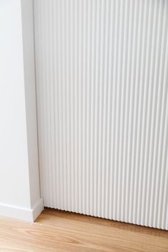 the corner of a room with a radiator and wood flooring in it