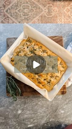 a square casserole dish on a wooden tray with rosemary sprigs in it