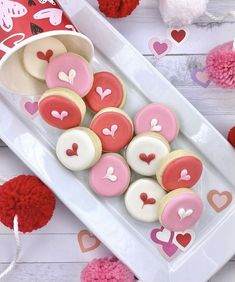 heart shaped cookies on a white plate next to pom poms and red hearts