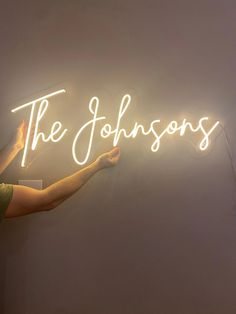 a person holding up a neon sign that says the johnsons