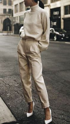 a woman standing in the middle of a street wearing high heels and a turtle neck sweater