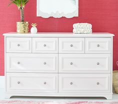 a white dresser sitting in front of a pink wall