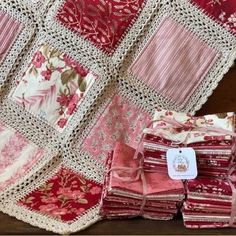 a pile of red and white quilts sitting on top of a wooden table