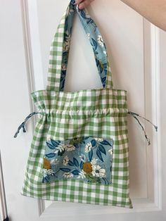 a person is holding onto a green and white tote bag with flowers on it