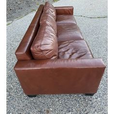 a brown leather couch sitting on top of a sidewalk