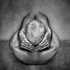 a black and white photo of two hands covering the top of a man's head