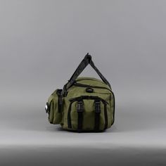 a green duffel bag sitting on top of a white table next to a gray wall