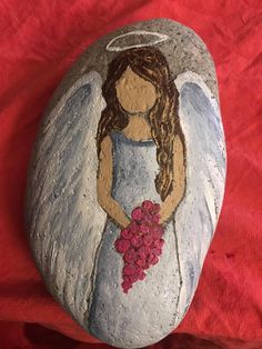 a painted rock with an angel holding flowers