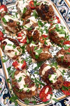 meatballs covered in sauce and garnished with fresh herbs on a platter