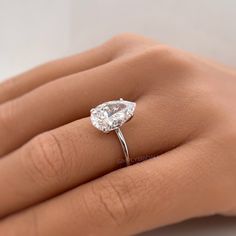 a woman's hand with a diamond ring on her left hand, showing the center stone