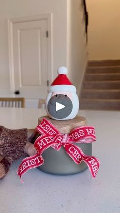 a teddy bear wearing a santa hat sitting on top of a bowl with a ribbon around it