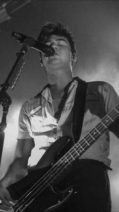 a man with a guitar in front of a microphone