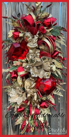 a red and gold christmas wreath on a wooden fence with holly berries, pine cones and other holiday decorations