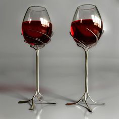 two wine glasses sitting next to each other with red liquid in the bottom and one empty