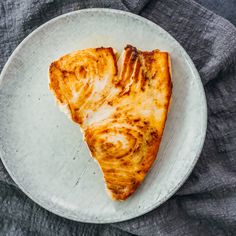 a piece of pizza sitting on top of a white plate next to a gray cloth