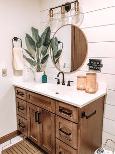 a bathroom vanity with two mirrors and a plant on it's side, in front of a white shiping wall