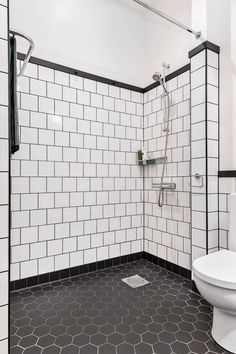 a bathroom with black and white tiles on the floor, shower head, and toilet