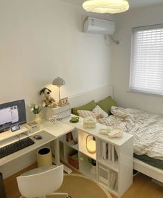 a bedroom with a bed, desk and computer on top of it in front of a window