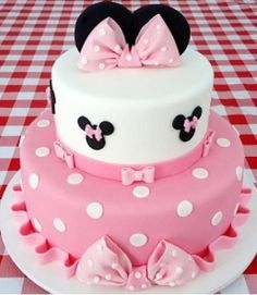 a pink and white cake with minnie mouse ears on top