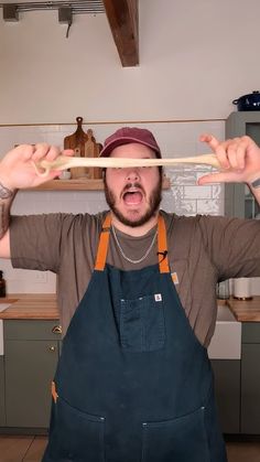 a man with an apron on holding two chopsticks over his head