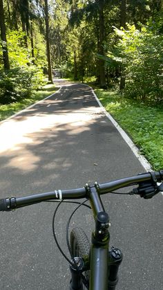 a bicycle is parked on the side of a road in the woods with grass and trees