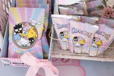 a basket filled with hello kitty bags next to some candy wrappers and a pink bow