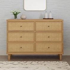 a wooden dresser sitting next to a mirror on top of a white rug in front of a wall