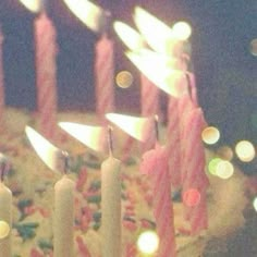 many candles are lit on a cake with pink frosting and sprinkles