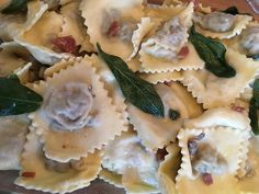 some ravioli with meat and spinach on a glass plate in front of a wooden table