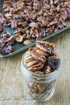 a jar full of pecans sitting on top of a table next to a tray