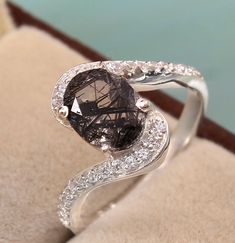 a fancy ring with a brown diamond and white diamonds on it's sides, sitting on top of a cushion