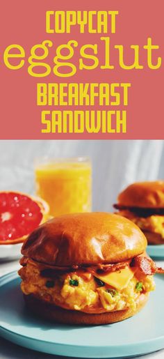 the breakfast sandwich has eggs and bacon on it, with orange juice in the background