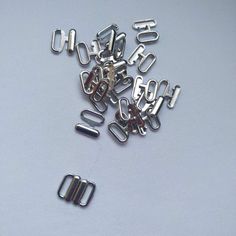 several metal clips are scattered on a white surface, with the letters cut out and placed next to each other