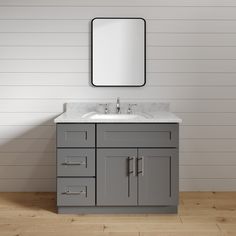 a bathroom vanity with a mirror above it and a wooden floor in front of the sink